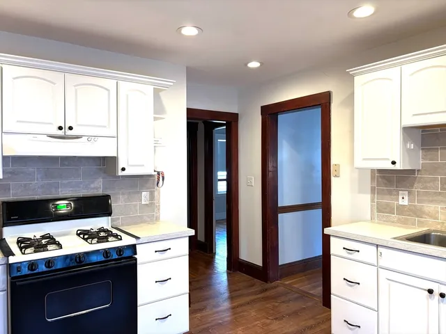 a kitchen with a stove and a wooden floor