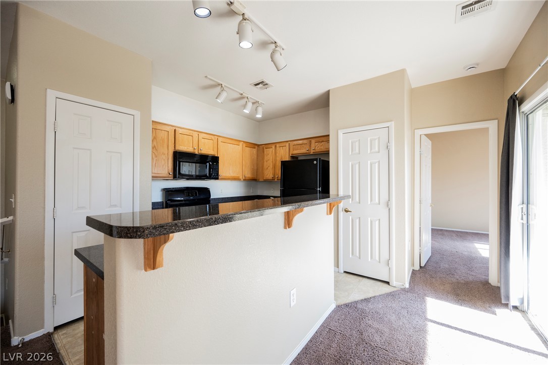 6320 Snap Ridge Street, Unit 201 North Las Vegas, NV 89081 - Photo 21 of 56 A functional kitchen features granite counters, track lighting, and a breakfast bar, seamlessly connecting to the living space.