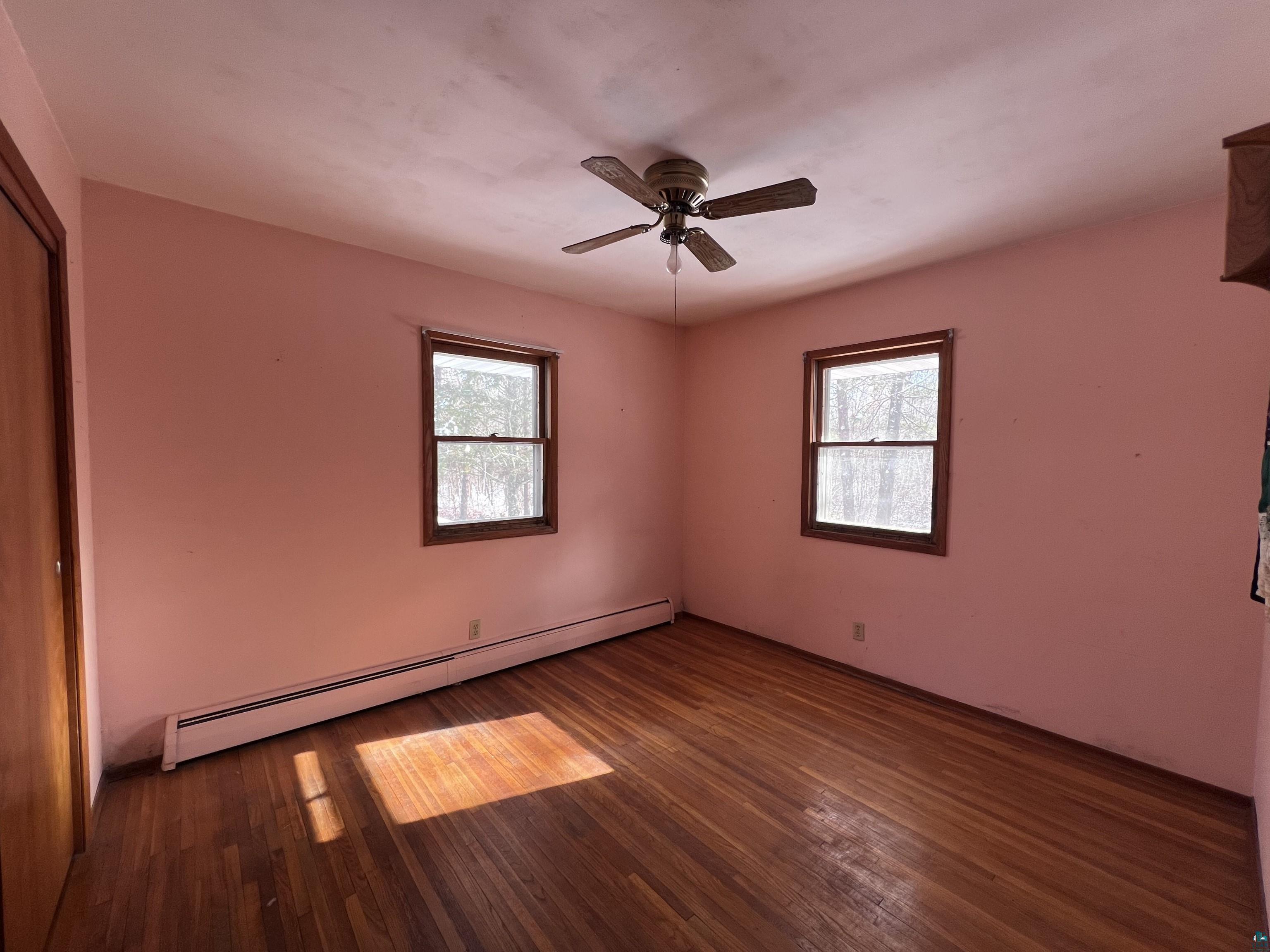 9278 Stone Chimney Road Solon Springs, WI 54873 - Photo 10 of 29 Unfurnished bedroom with ceiling fan, multiple windows, dark hardwood / wood-style floors, and a baseboard radiator