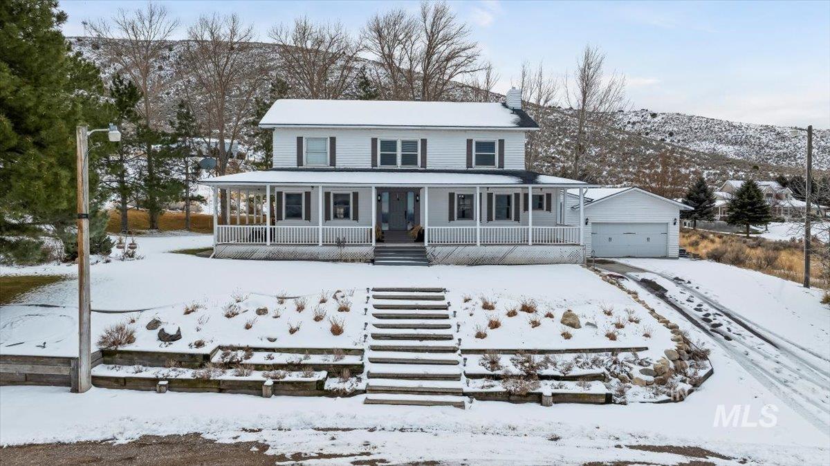 Farmhouse-style home with a porch, a mountain view, a garage, and a chimney