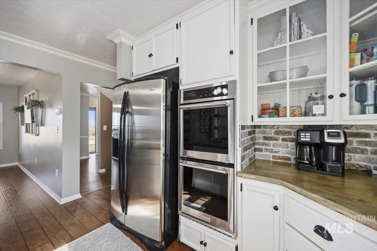 899 East 500th Street South Declo, ID 83323 - Photo 19 of 50 Kitchen with white cabinets, stainless steel appliances, glass fronted cabinets, a textured ceiling, and ornamental molding