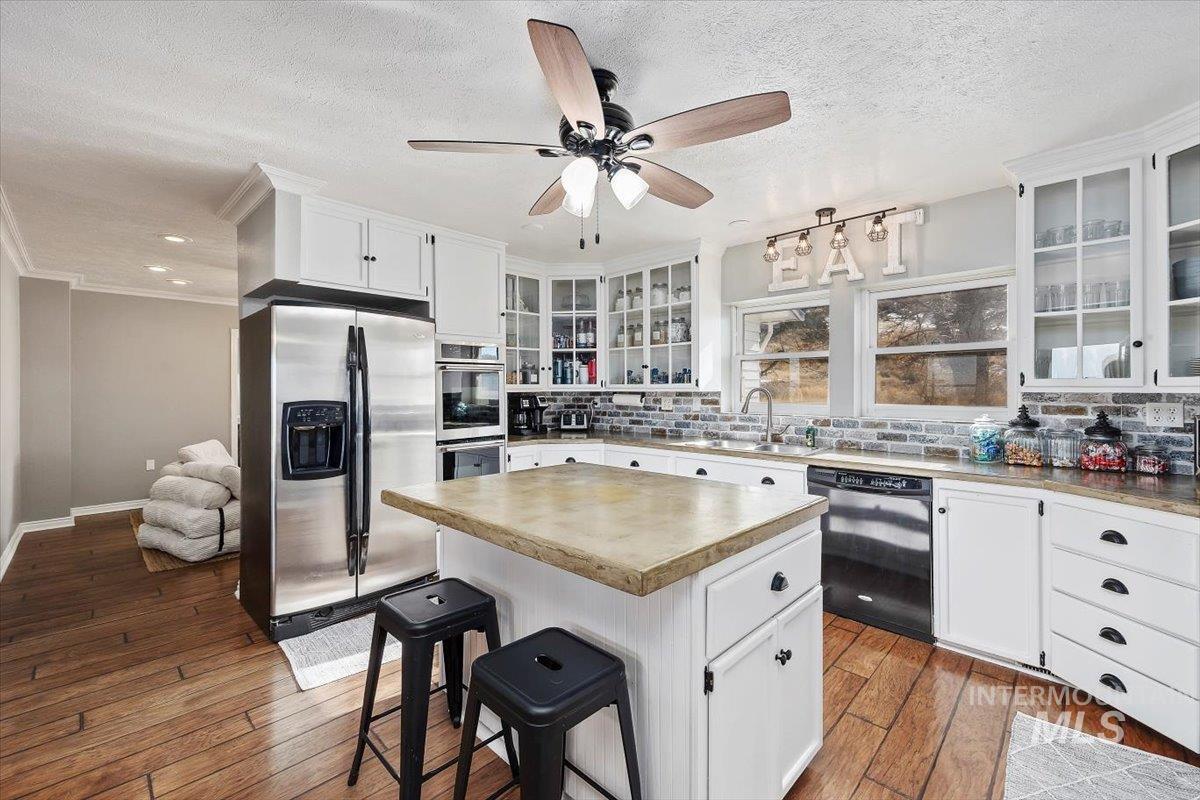 899 East 500th Street South Declo, ID 83323 - Photo 21 of 50 Kitchen with white cabinetry, stainless steel appliances, light countertops, tasteful backsplash, and a kitchen bar