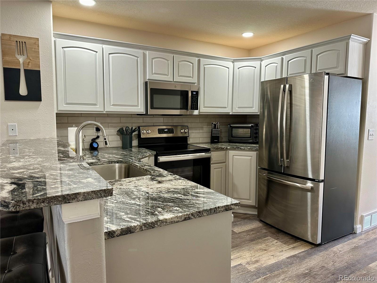 a kitchen with stainless steel appliances granite countertop a refrigerator stove microwave sink and cabinets