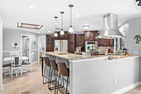 a kitchen with stainless steel appliances kitchen island granite countertop a table chairs and a view of living room