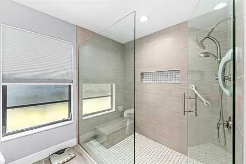 a bathroom with a glass shower door and a window