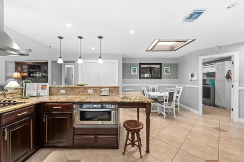 a kitchen with stainless steel appliances kitchen island granite countertop a table chairs and a view of living room