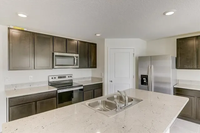 a kitchen with stainless steel appliances kitchen island granite countertop a sink stove and refrigerator