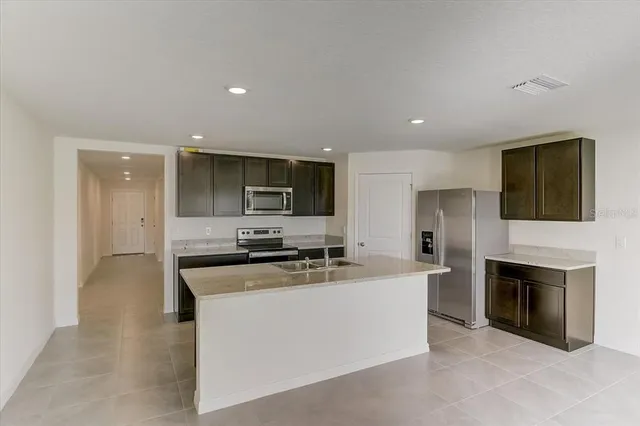 a kitchen with stainless steel appliances a stove top oven a sink a refrigerator and a oven