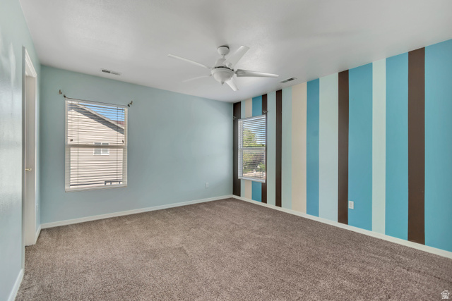 546 Wheatridge Road Tooele, UT 84074 - Photo 27 of 49 2nd Bedroom featuring a ceiling fan, two windows with blinds, light blue walls, and a prominent accent wall