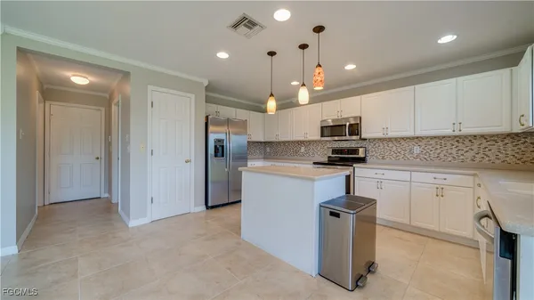 a kitchen with kitchen island granite countertop a refrigerator oven a sink and white cabinets