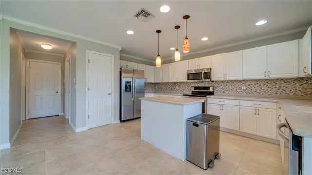 a kitchen with kitchen island granite countertop a refrigerator oven a sink and white cabinets