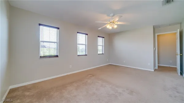 an empty room with windows and fan
