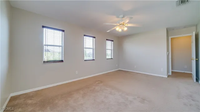 an empty room with windows and fan
