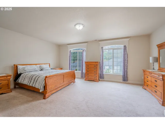 a spacious bedroom with a bed and dresser