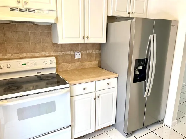 a white refrigerator freezer and a stove sitting inside of a kitchen
