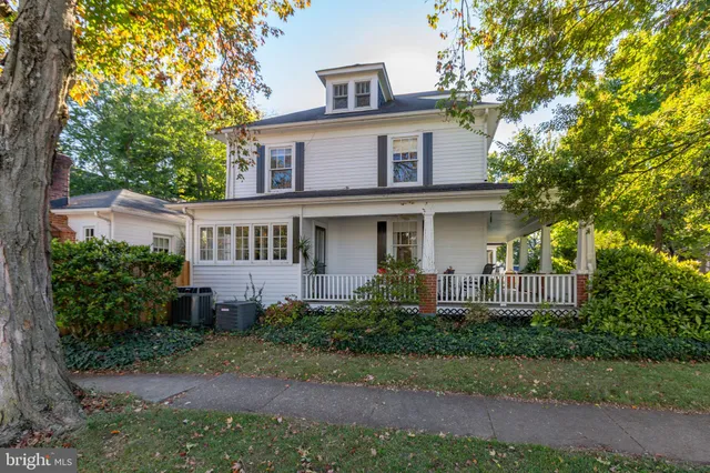 a view of a house with a yard and large trees