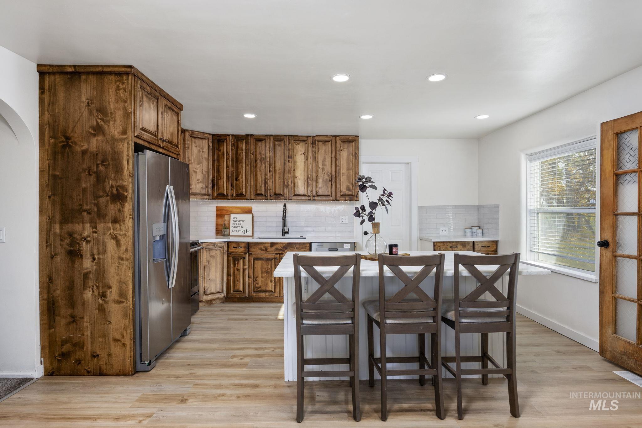 128 South 100 East Rupert, ID 83350 - Photo 12 of 44 Kitchen with backsplash, a kitchen bar, light wood-style floors, stainless steel appliances, and recessed lighting