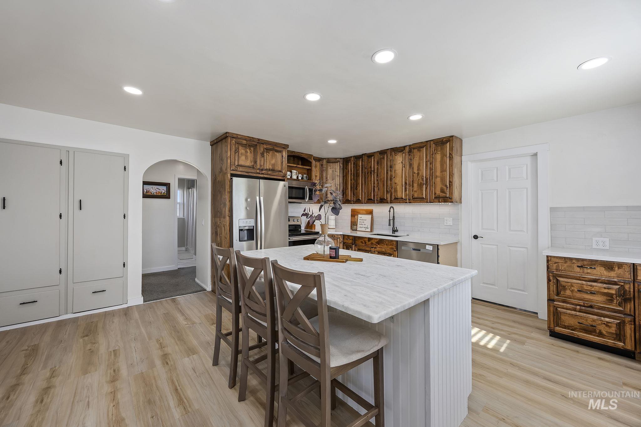 128 South 100 East Rupert, ID 83350 - Photo 13 of 44 Kitchen with arched walkways, stainless steel appliances, backsplash, recessed lighting, and a kitchen bar