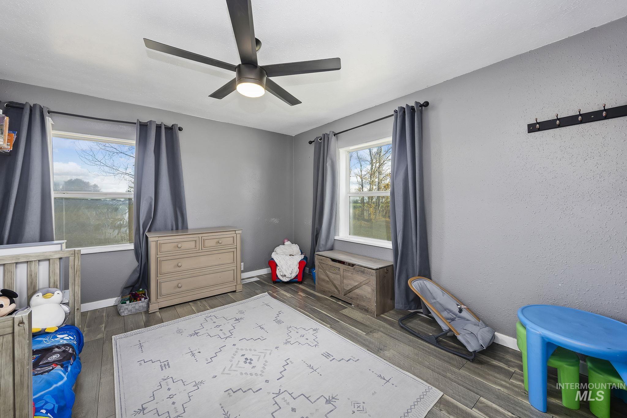 128 South 100 East Rupert, ID 83350 - Photo 19 of 44 Bedroom featuring dark wood finished floors, a ceiling fan, a nursery area, and a textured wall