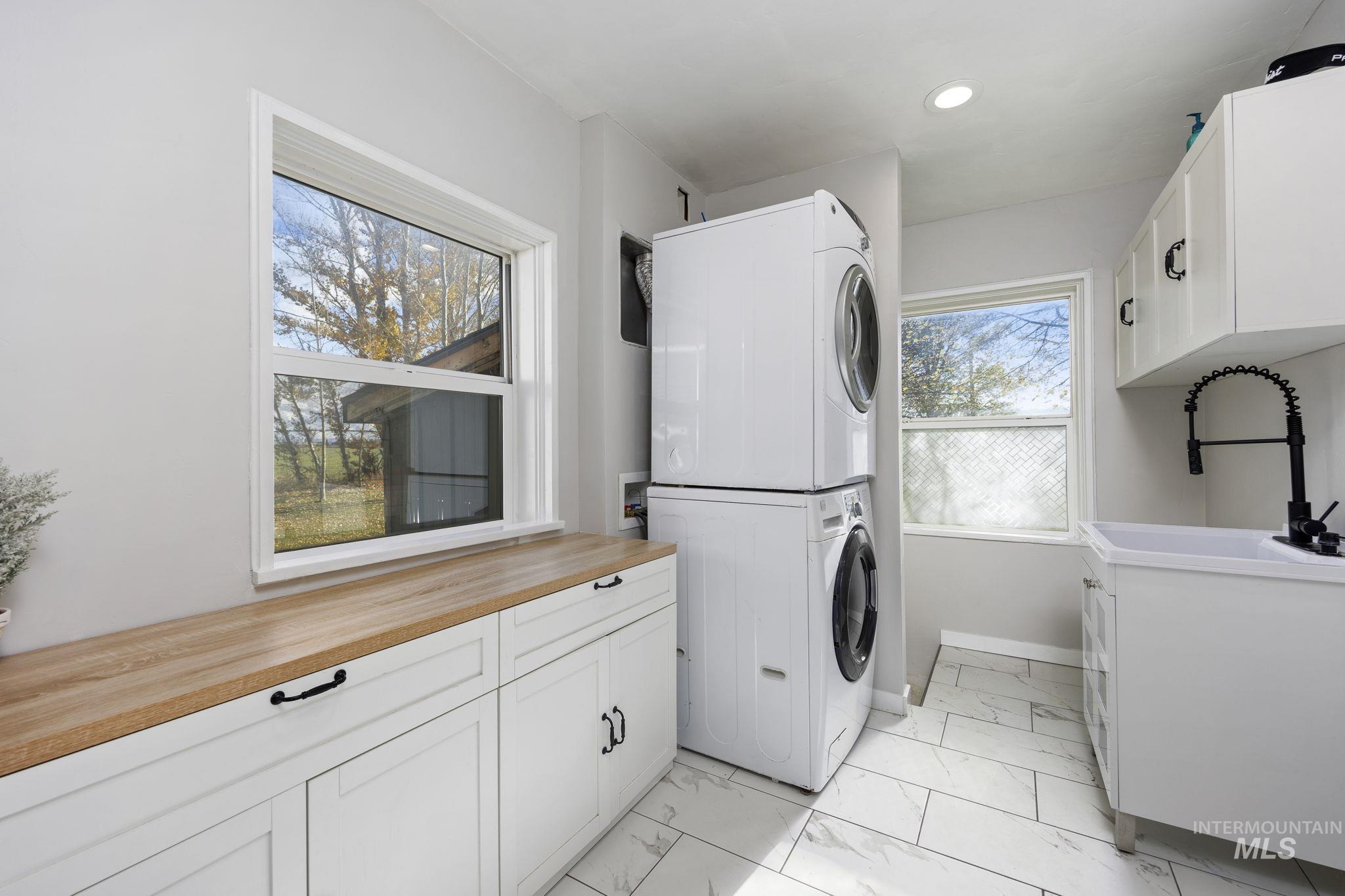 128 South 100 East Rupert, ID 83350 - Photo 26 of 44 Washroom with cabinet space, stacked washer and clothes dryer, light marble finish flooring, and recessed lighting