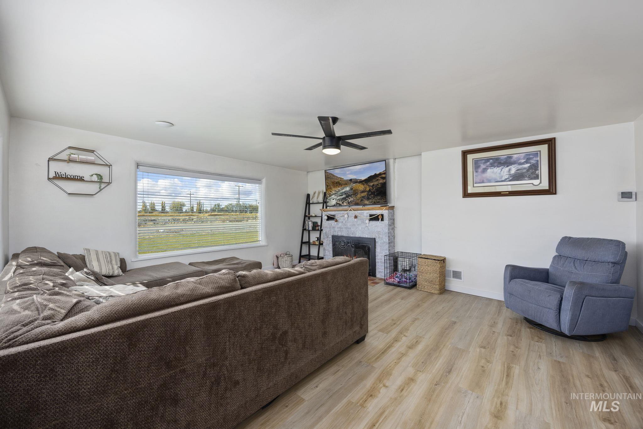 128 South 100 East Rupert, ID 83350 - Photo 6 of 44 Living area featuring light wood-type flooring, a fireplace, and a ceiling fan
