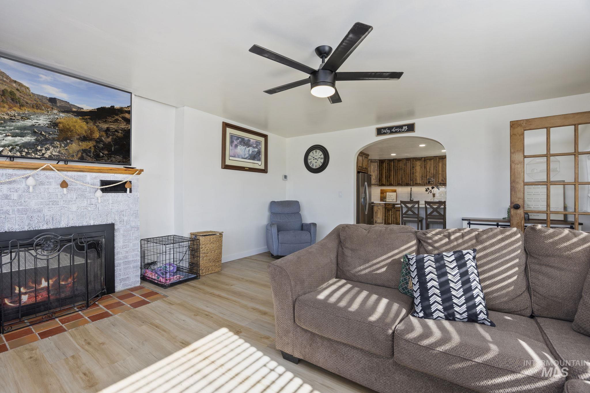 128 South 100 East Rupert, ID 83350 - Photo 10 of 44 Living area featuring arched walkways, wood finished floors, a fireplace, and a ceiling fan