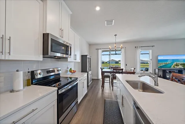 a living room with furniture a wooden floor and kitchen view