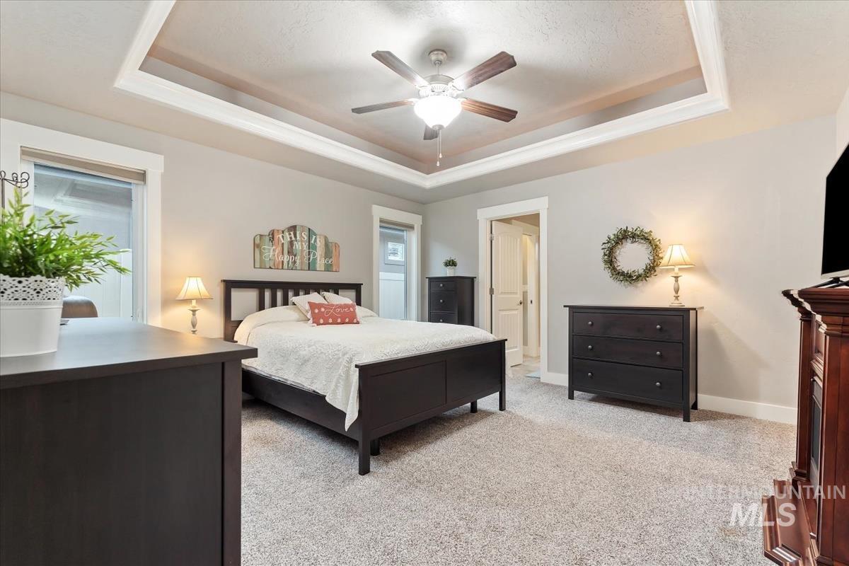1447 West Arch Rock Street Meridian, ID 83646 - Photo 17 of 43 Bedroom featuring light colored carpet, a raised ceiling, and ceiling fan
