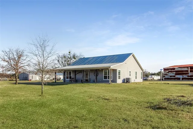 a view of a house with a big yard and large trees