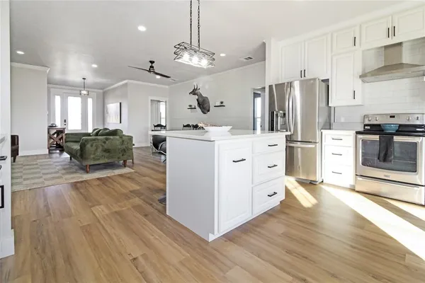 a kitchen with stainless steel appliances kitchen island wooden floors and white cabinets