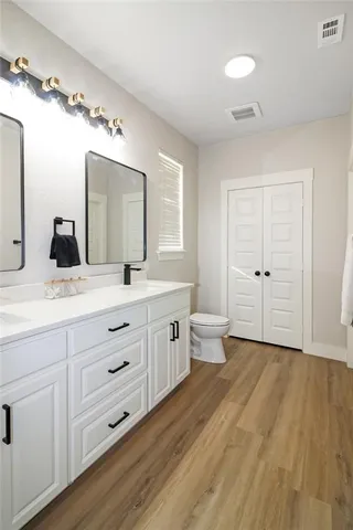 a spacious bathroom with double vanity sink a mirror and a toilet