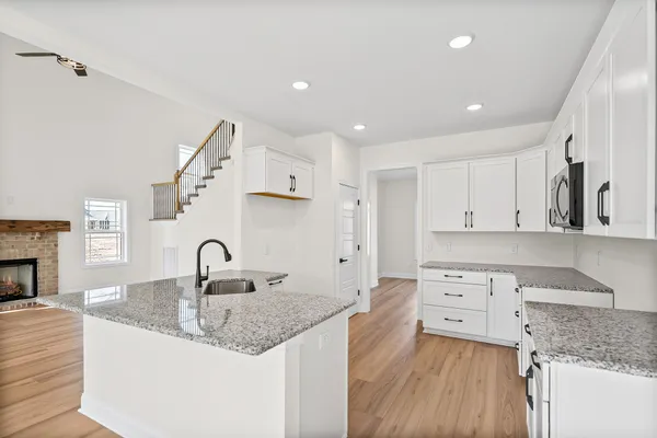 a kitchen with stainless steel appliances granite countertop a stove a sink and white cabinets