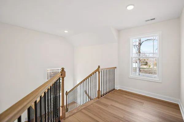 a view of a hallway with wooden floor and staircase