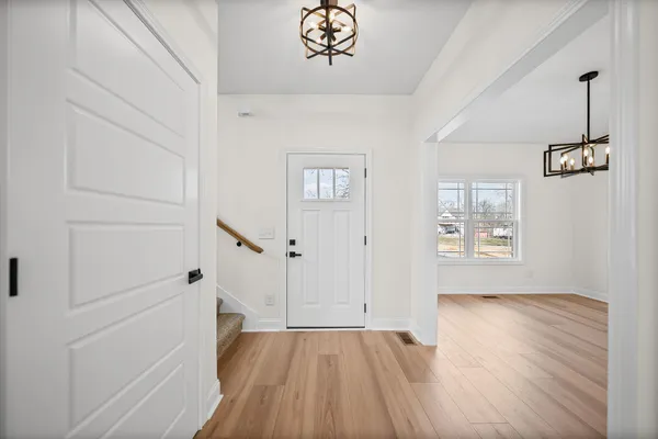 a view of a room with wooden floor chandelier and a ceiling fan