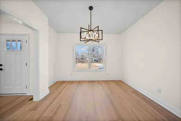 a view of a hallway with wooden floor and a chandelier