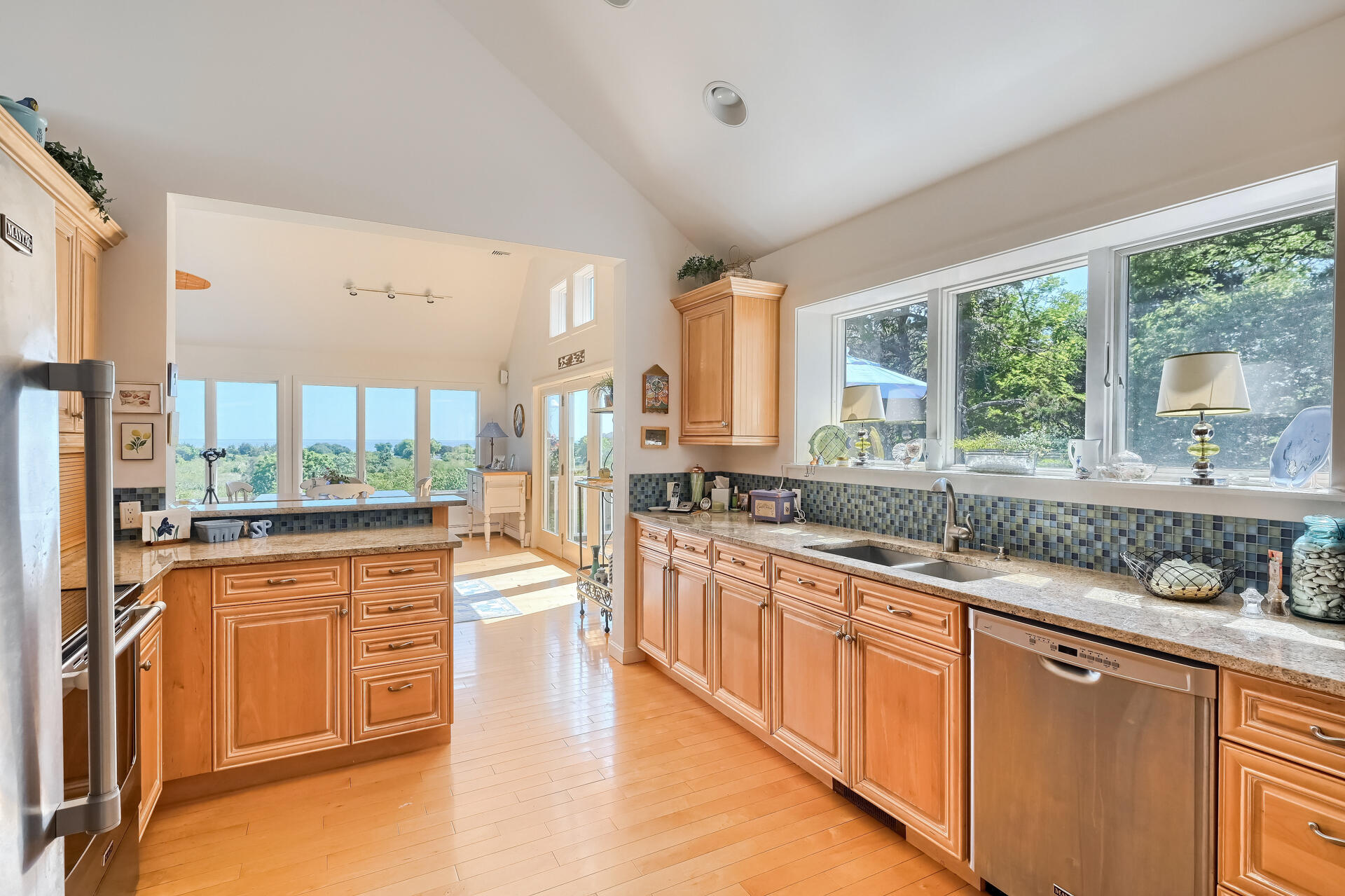 95 Chequessett Neck Road Wellfleet, MA 02667 - Photo 23 of 75 a large kitchen with stainless steel appliances granite countertop a stove a sink dishwasher a refrigerator white cabinets and wooden floor next to a window