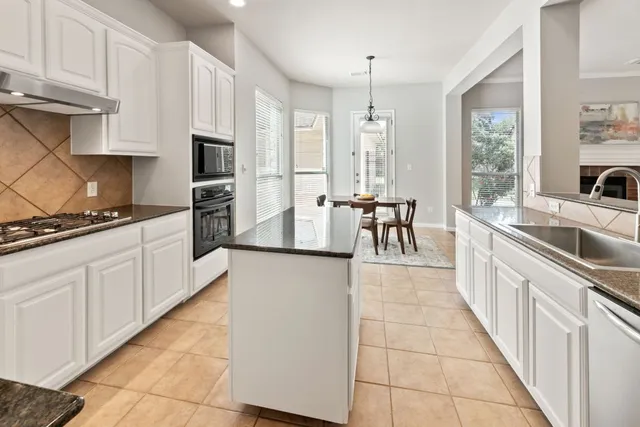 a large white kitchen with stainless steel appliances granite countertop a stove and a sink