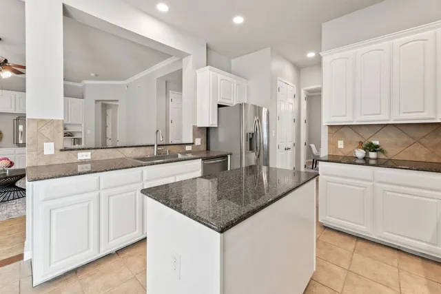 a kitchen with stainless steel appliances granite countertop a sink a stove a refrigerator and white cabinets