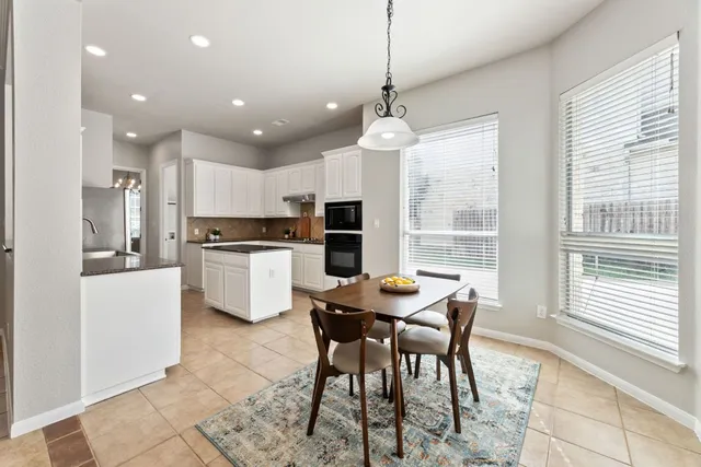 a kitchen with stainless steel appliances kitchen island granite countertop a stove a sink a refrigerator with a dining table and chairs