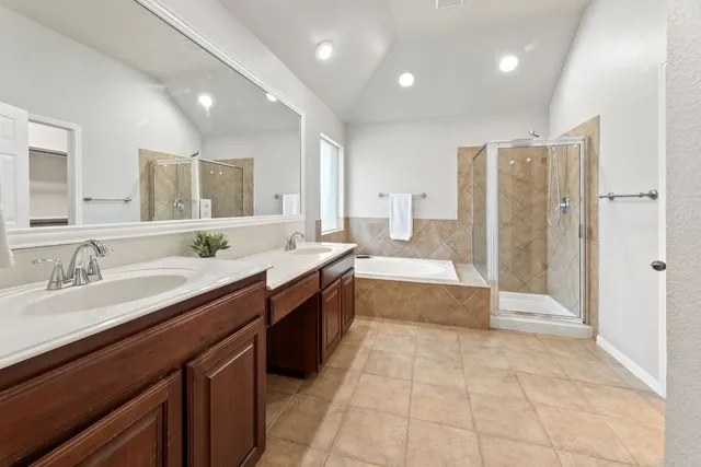 a large bathroom with a granite countertop double vanity sink a mirror and a bathtub