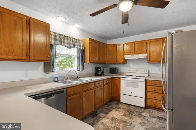 a kitchen with stainless steel appliances granite countertop a sink a stove and refrigerator