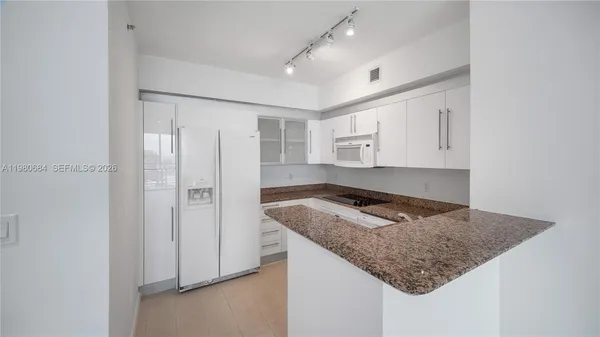 a kitchen with granite countertop a sink and refrigerator