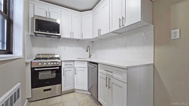 a kitchen with white cabinets and stainless steel appliances