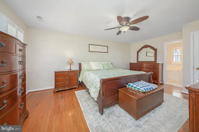 a bedroom with a bed and a dresser with wooden floor