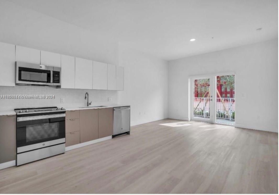 110 Foster Road, Unit 109B Hallandale Beach, FL 33009 - Photo 2 of 12 a kitchen with stainless steel appliances granite countertop a stove a sink and a microwave