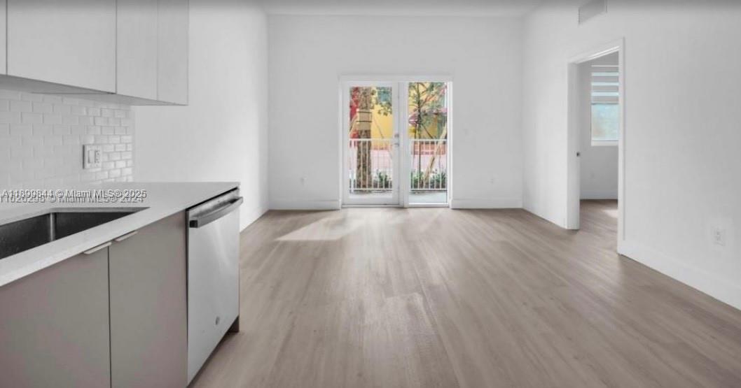 110 Foster Road, Unit 109B Hallandale Beach, FL 33009 - Photo 4 of 12 a view of an empty room with window and wooden floor