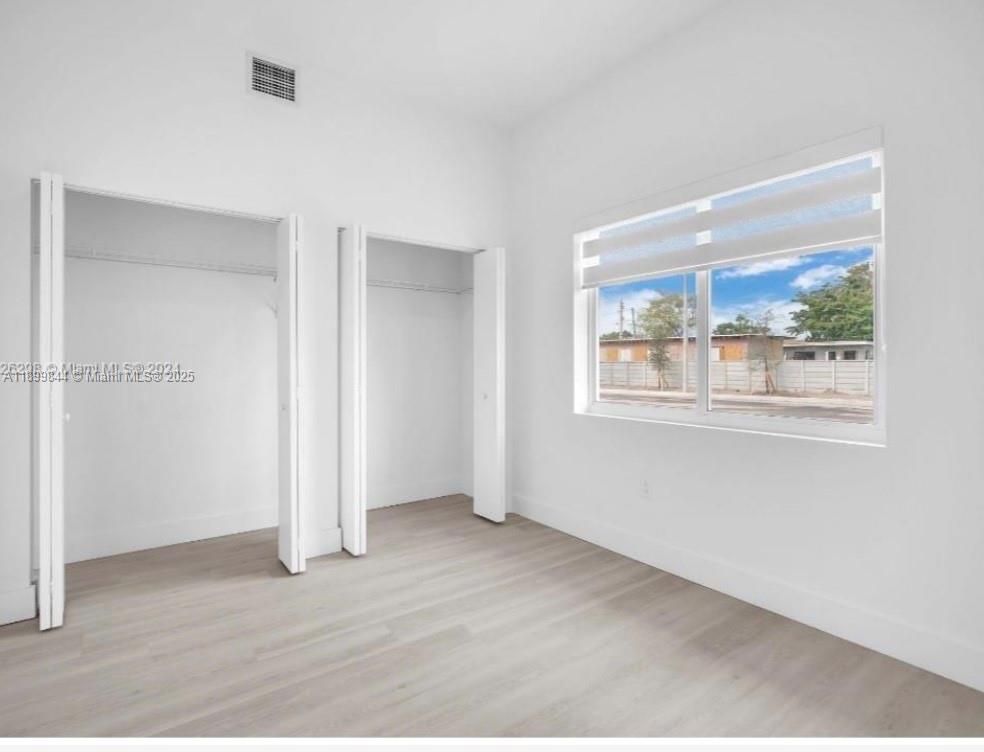 110 Foster Road, Unit 109B Hallandale Beach, FL 33009 - Photo 10 of 12 an empty room with wooden floor and windows