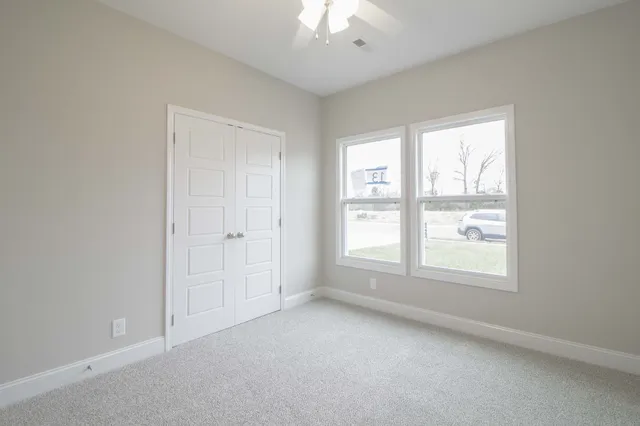 an empty room with a window and a chandelier fan