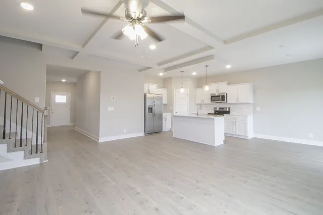 a view of an empty room and kitchen view