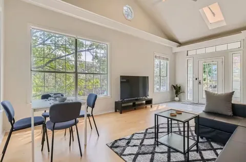 a living room with furniture a flat screen tv and a large window